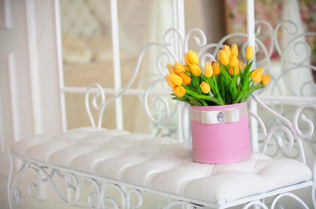 Roze doos met gele tulpen in een wit interieur