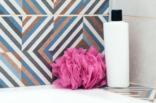 Foto roze douche puff fles van cosmetisch product in de badkamer