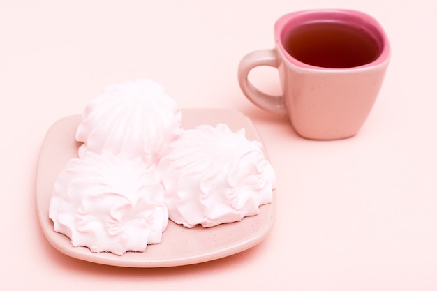 Roze drankje in een koffiekopje en marshmallows op een schotel. Kopieer ruimte