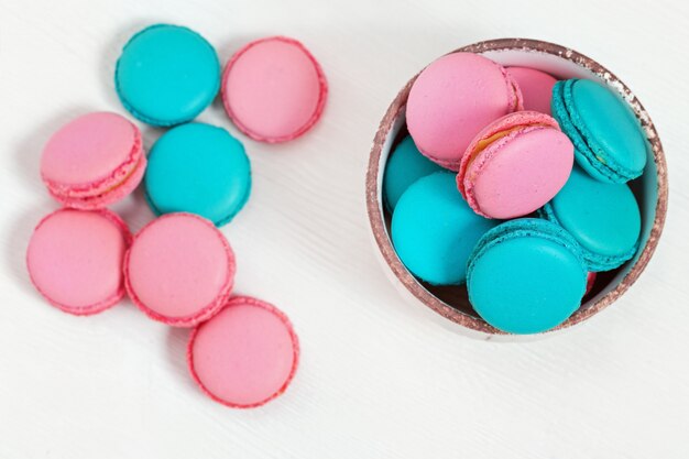 Roze en blauwe amandelkoekjes macarons in plaat op witte houten lijst met exemplaarruimte. Knapperig zoet dessert. Bovenaanzicht