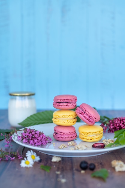 Roze en gele Macarons op witte plaat op een houten oppervlak