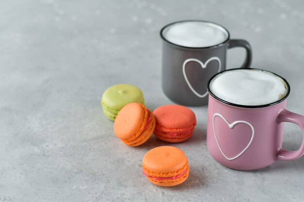 Roze en grijze kopjes met cappuccino en macarons