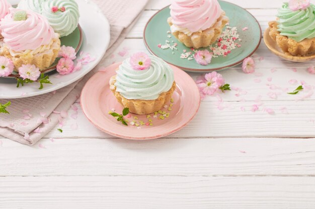 Roze en groene cupcakes met Lentebloemen op witte houten achtergrond