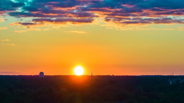 Roze en paarse wolken met oranje en gele hemel en gouden zon ondergaan op het bos horizon aerial