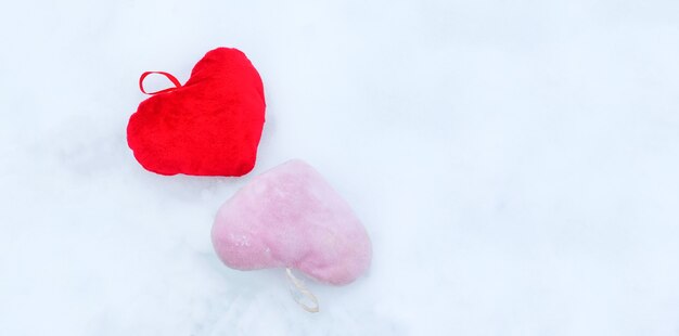 Roze en rode pluche decoratieve harten op sneeuw