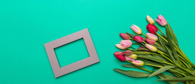 Roze en rood tulpenboeket en leeg frame op groene achtergrond banner bovenaanzicht