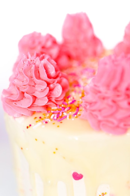 Roze en witte buttercream cream cake met roze hagelslag en witte chocolade ganache drip.