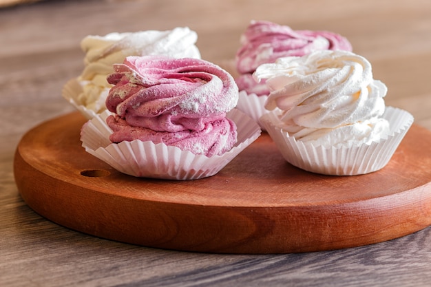 Roze en witte marshmallows op een ronde houten bord