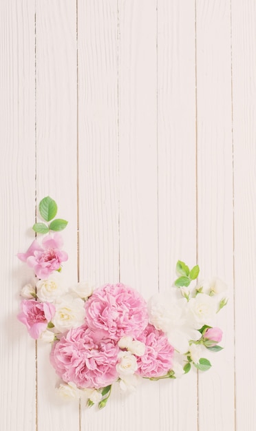 Roze en witte rozen op witte houten muur