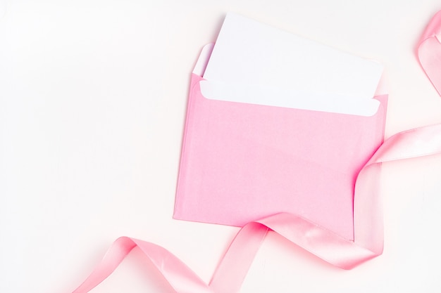 Roze envelop en satijnen lint op een lichte achtergrond.