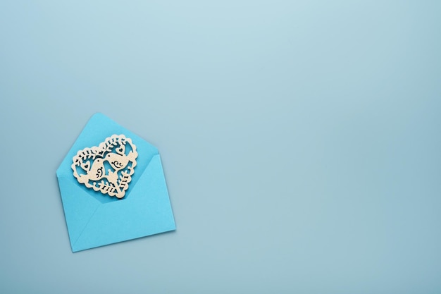 Roze envelop met wit opengewerkt hart op lichtblauwe achtergrond. Bovenaanzicht met kopie ruimte. Valentijnsdag of bruiloft romantisch concept. Feestelijke compositie. Bespotten.