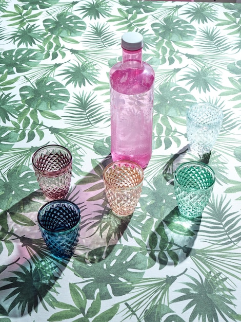 Foto roze fles water en kleurrijke glazen op een bloementafelkleed