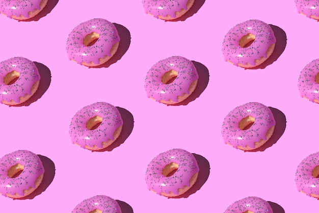 Roze geglazuurd donutpatroon op pastel.