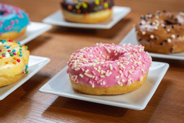 Roze geglazuurde donut op een witte plaat die op een houten tafel staat