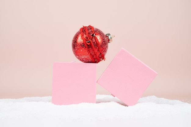 Roze geschenkdozen en rode bal in de sneeuw op pastel oppervlak. Kerstkaart. Hoge kwaliteit foto