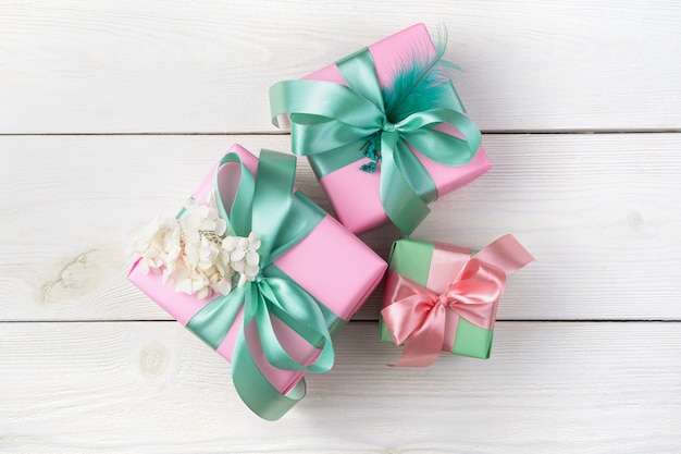 Roze geschenkdozen met linten op een witte houten achtergrond. Bovenaanzicht, met ruimte om te kopiëren.