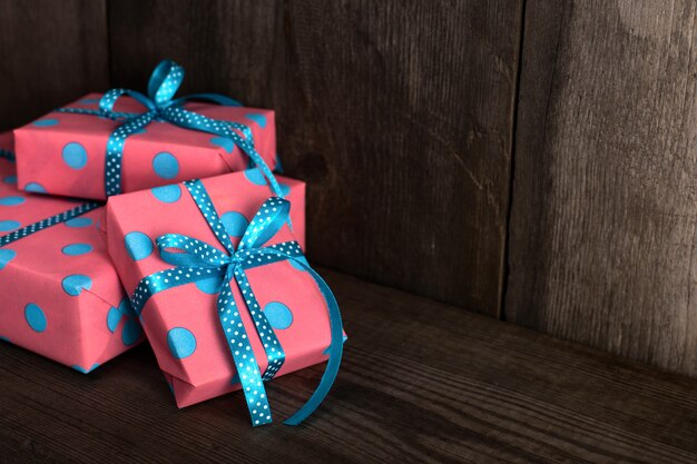 Roze geschenken met blauw lint op een oud houten boekenrek.