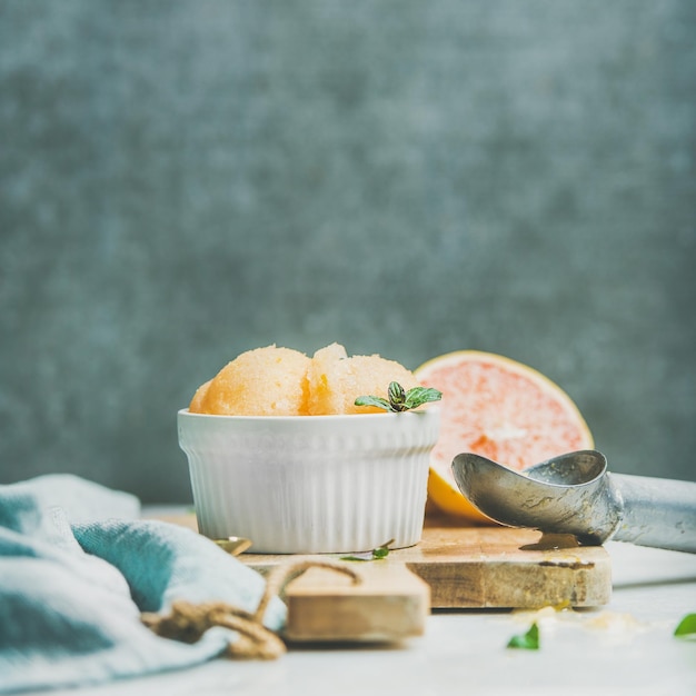 Roze grapefruitsorbet met munt in kom op houten plank