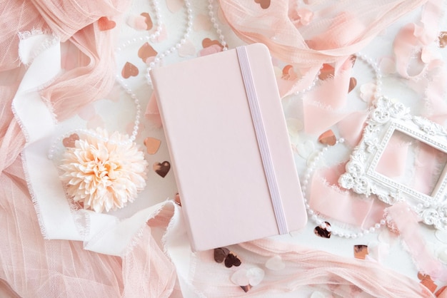 Foto roze hardcover notebook in de buurt van harten en romantisch roze decor top view leerboek mockup