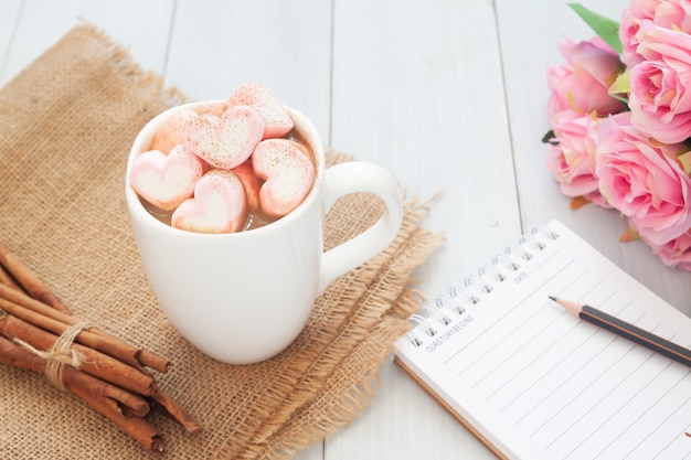 Roze hart vorm marshmallow op warme drank met rozen en een notebook. Liefde en Valentijnsdag concept