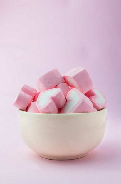 Roze hartvormige marshmallows binnen met roze achtergrond