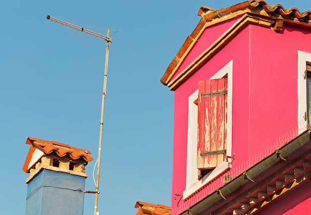 Roze huis met tv-antenne onder een blauwe lucht
