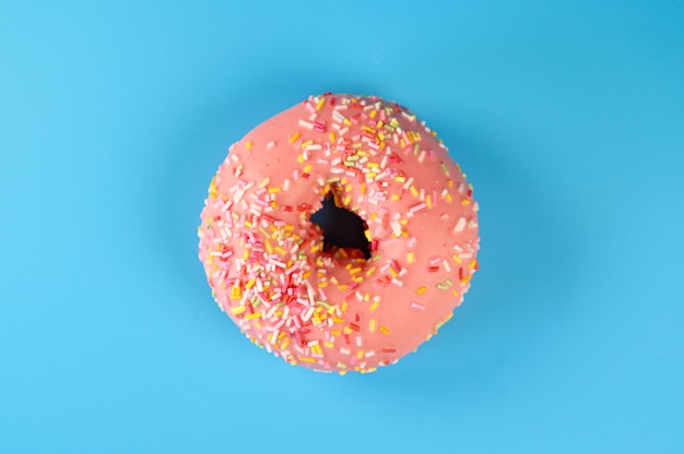 Roze iced donut op blauwe achtergrond. Zoet dessert bovenaanzicht.