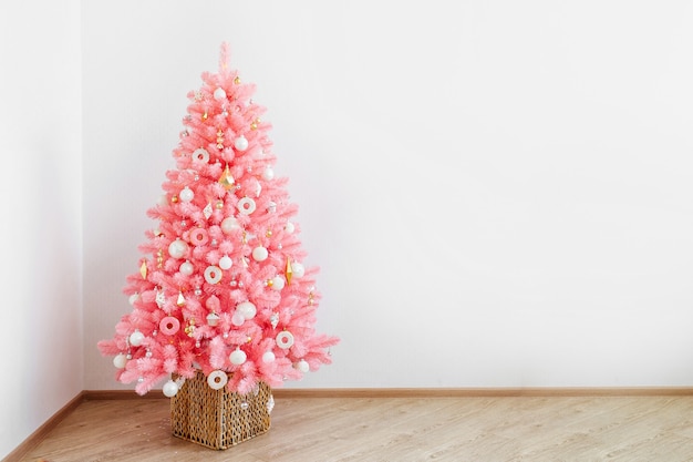 Roze kerstboom en kerstversiering wit en goud kleur in wit interieur