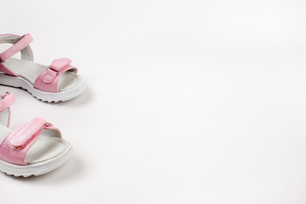 Roze kindersandalen van glanzend leer met klittenbandsluiting platte witte zolen geïsoleerd op een w...