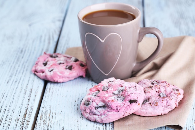 Roze koekjes en kopje koffie op tafel close-up