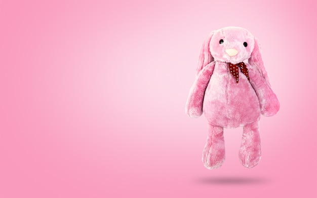 Roze konijnpop met afluisteraar op zoete achtergrond. Leuk knuffeldier en pluizig bont voor kinderen.