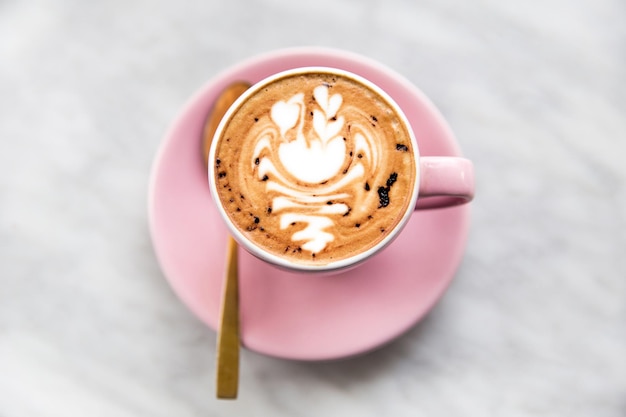 Roze kopje cappuccino met zwaan latte art op marmeren tafel achtergrond