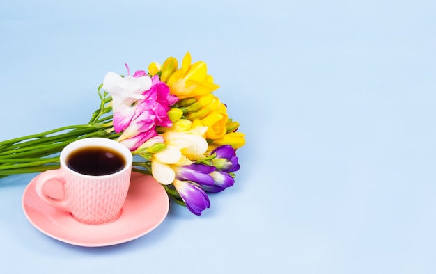 Roze kopje koffie met kleurrijk bloemboeket op lichtblauwe achtergrond