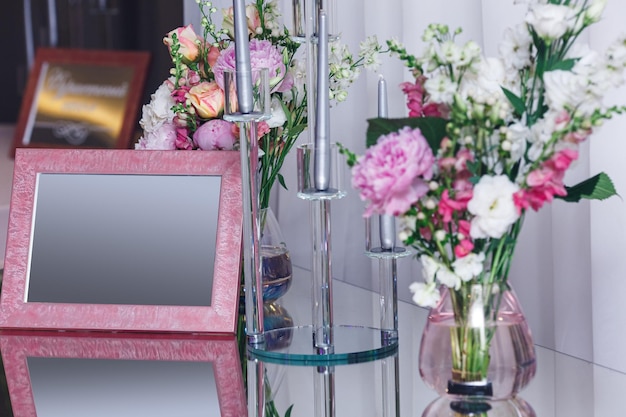 Roze leeg frame en bloemen in een vaas op een spiegeltafel