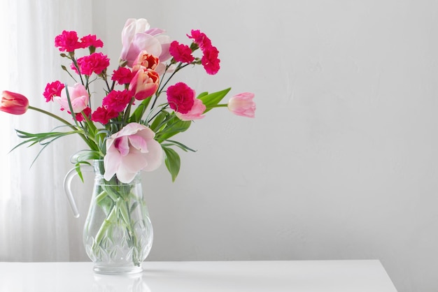 Roze Lentebloemen in glazen kan op witte achtergrond