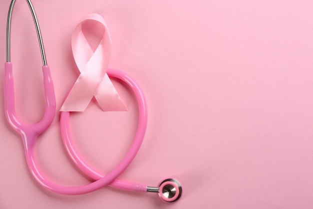 Roze lint als symbool voor borstkankerbewustzijn en stethoscoop op een platte achtergrond met kleur lag Ruimte voor tekst
