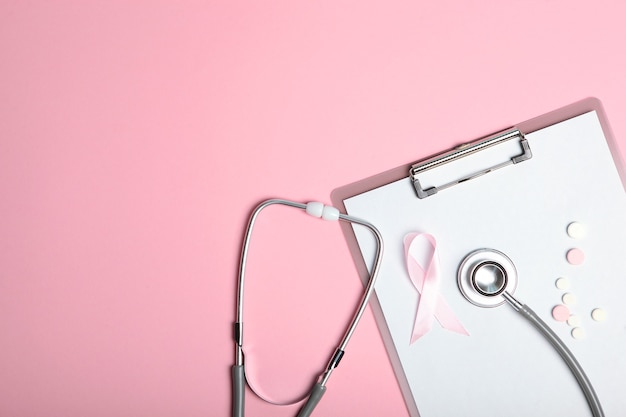 Roze lint en stethoscoop op een gekleurde achtergrond bovenaanzicht kankerziekte