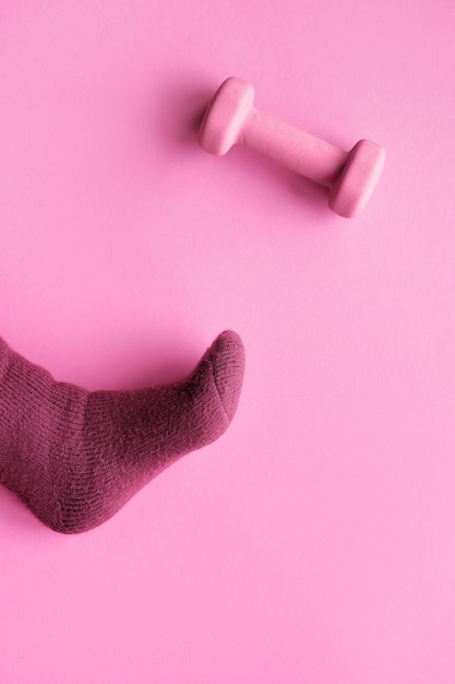 Roze magenta monochrome abstracte papier achtergrond met voet in warme sok en dumbbell