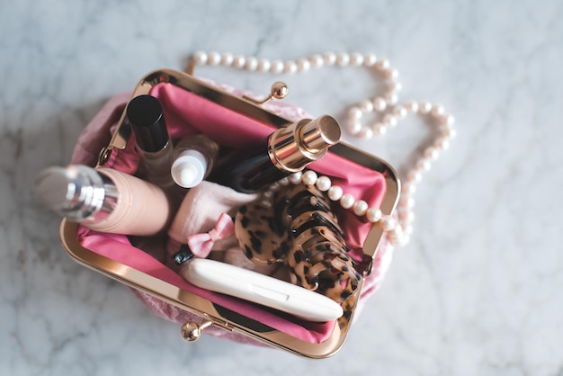 Roze make-up tas vullen met make-up producten en sieraden op marmeren tafelblad weergave close-up Beauty concept