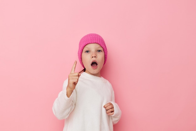 Roze meisjehoed op haar hoofd die roze achtergrond stelt