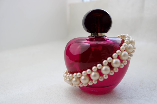 Roze mooie glazen transparante fles vrouwelijk parfum versierd met witte kostbare parels