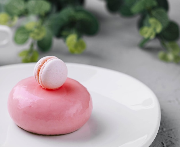 Roze mousse taart versierd met witte macaroon