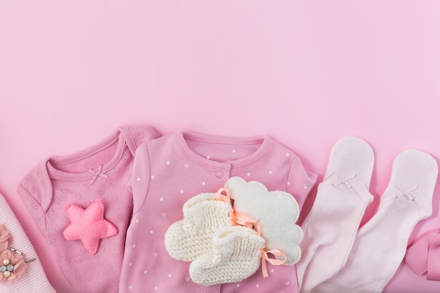 Roze muur met kleding, sokken en speelgoed voor een pasgeboren meisje.