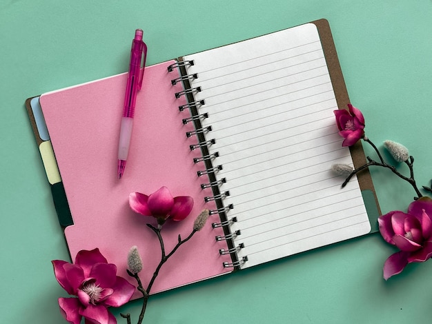 Foto roze notitieboek met pen bovenop roze magnolia bloemen