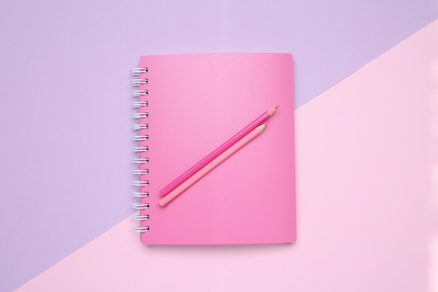 Roze notitieboekje en potloden op kleur achtergrond bovenaanzicht