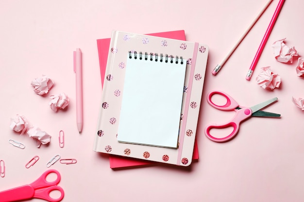 Roze notitieboekje op een roze achtergrond met roze schoolspullen. Plaats voor tekst. Bovenaanzicht.