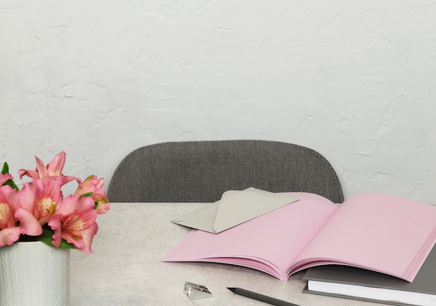 Roze notities, boek, envelop, bloemen op grijs bureau