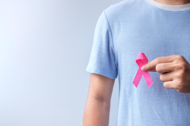 Roze oktober breast cancer awareness maand man houdt roze lint vast voor ondersteuning van het leven en de ziekte van mensen nationale kankeroverlevenden maand moeder en wereldkankerdagconcept