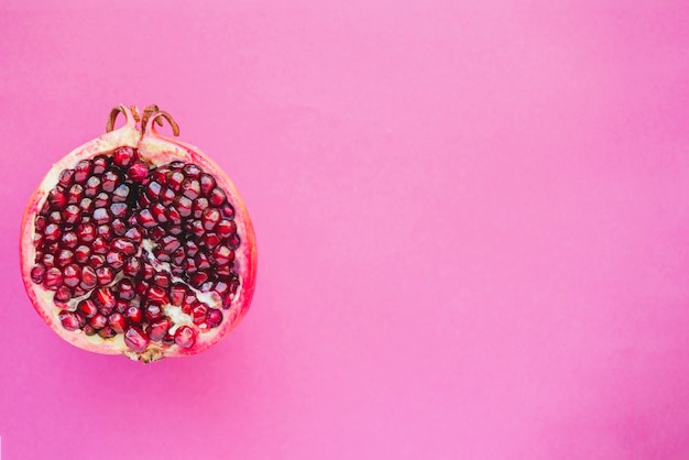 Foto roze oppervlak met granaatappel en lege ruimte