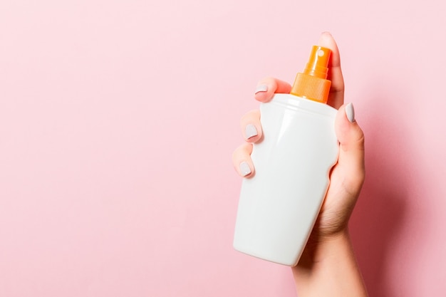 Roze oppervlak met vrouwelijke hand met cosmetica spray en kopieer ruimte voor uw ontwerp